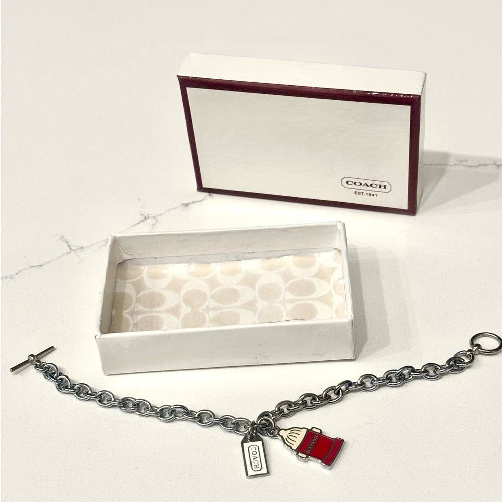 NIB Coach Silver Bracelet with two Charms includes original box and tissue.